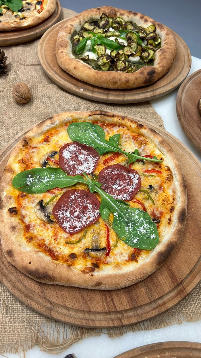 Gourmet pizzas with fresh toppings like salami, arugula, mushrooms, and more, perfectly baked and ready to serve.